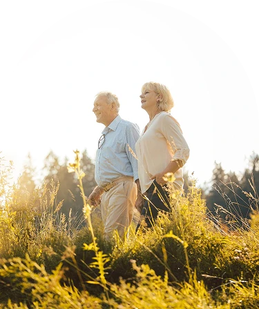 An elderly couple stands in a field.