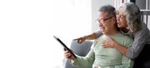 Senior man sitting comfortably on a couch and using a laptop to stay connected and informed through technology.